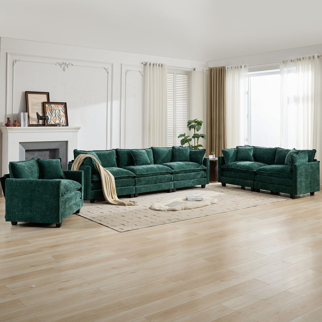 Green velvet sofa set in a living room with wooden floor and large windows.