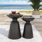 Two black outdoor side tables with a cup and book on a patio with ocean view