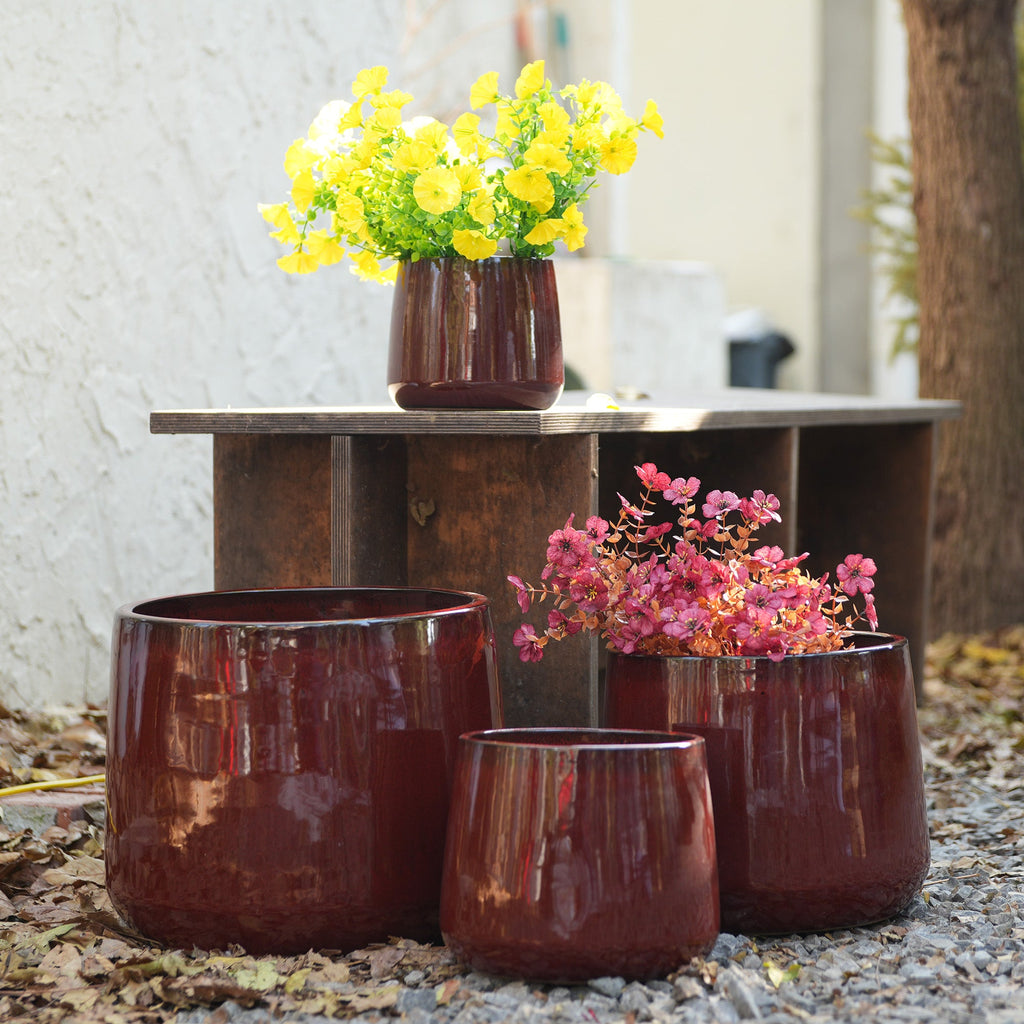 Set of brown ceramic planters with flowers on a stone surface