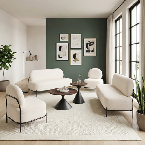 Modern living room with white furniture, black tables, and framed art on a green wall.