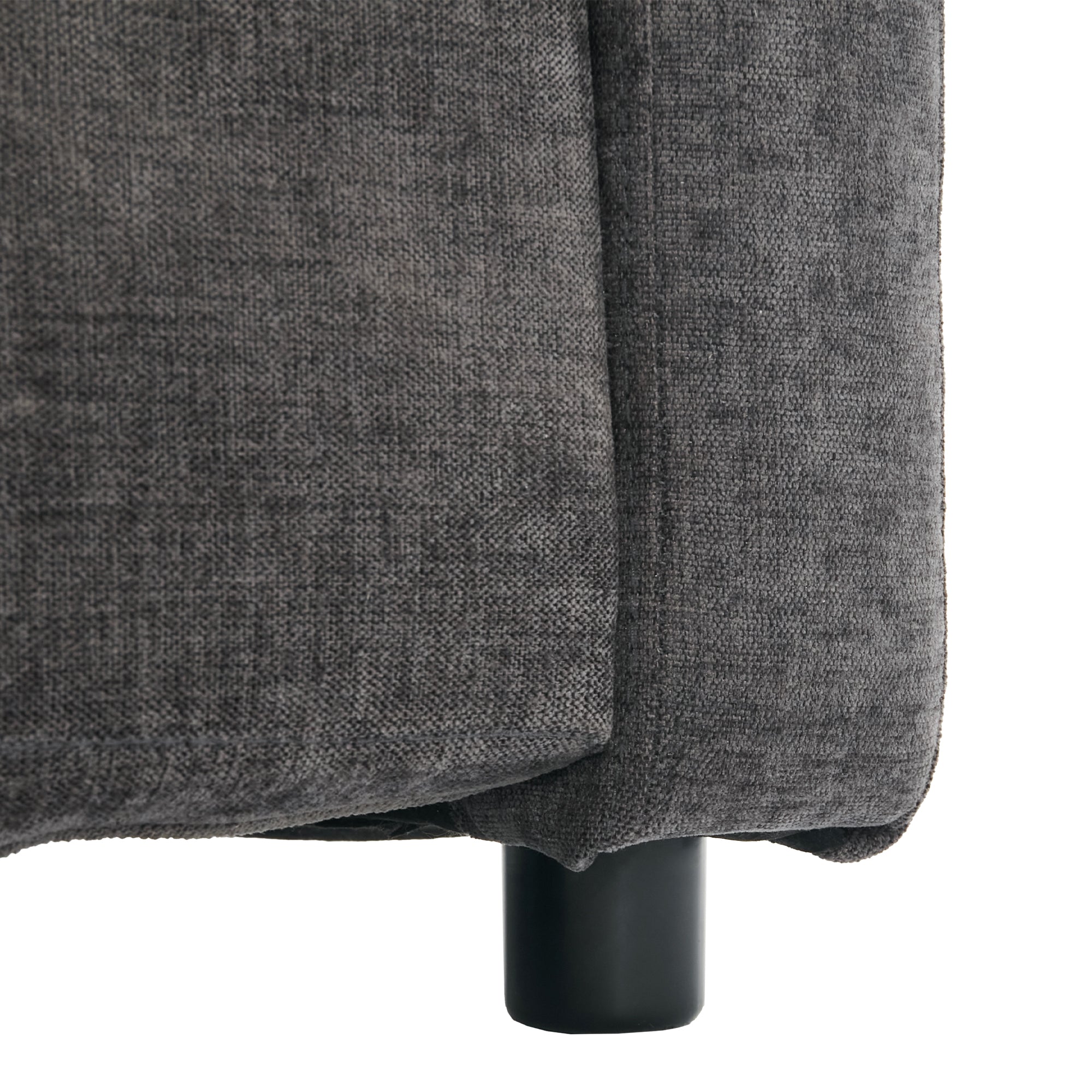 Close-up of a gray upholstered chair corner with a black leg on a white background