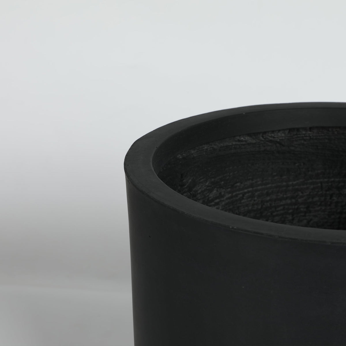 Black cylindrical planter on a light gray background