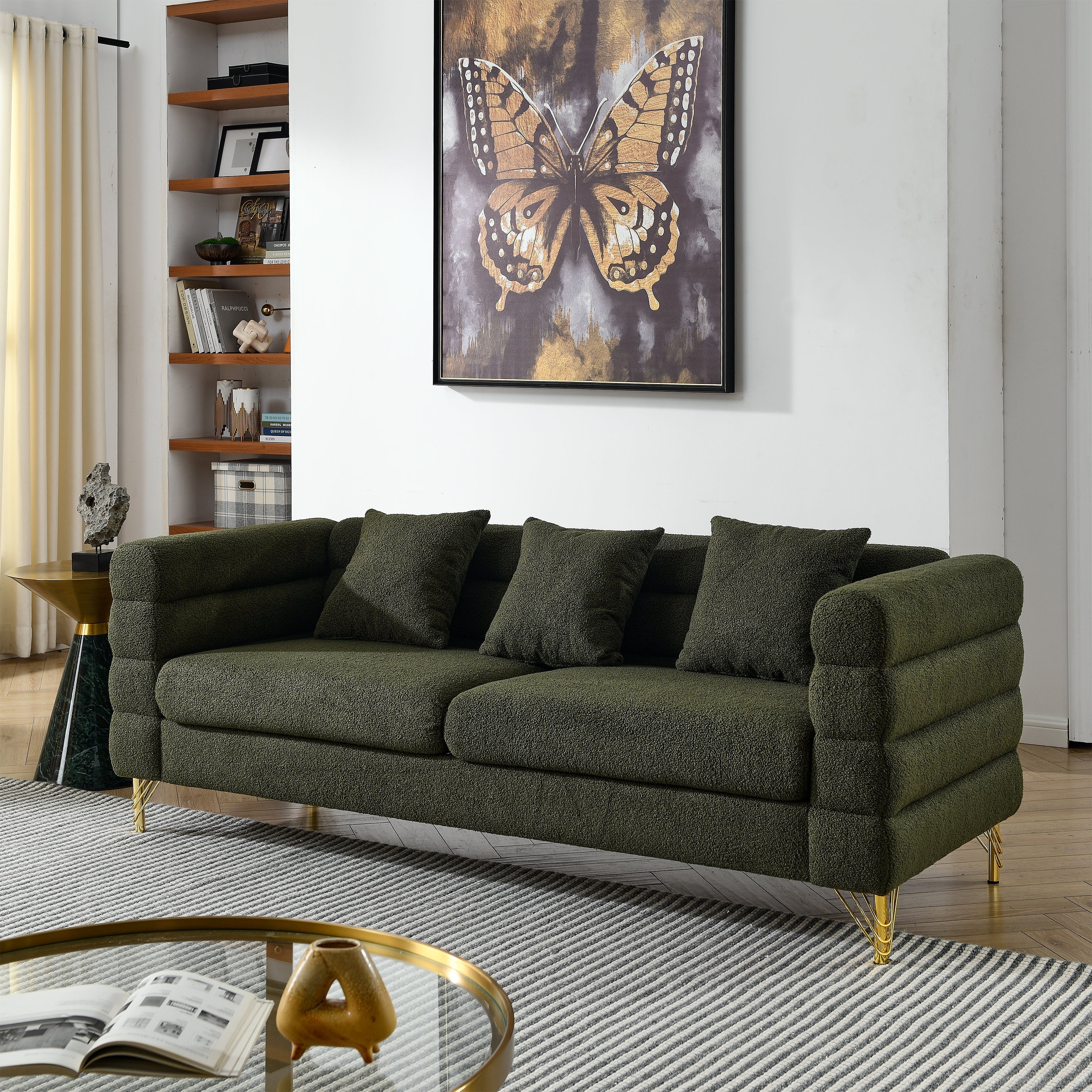 Green sofa in a living room with a butterfly artwork on the wall.