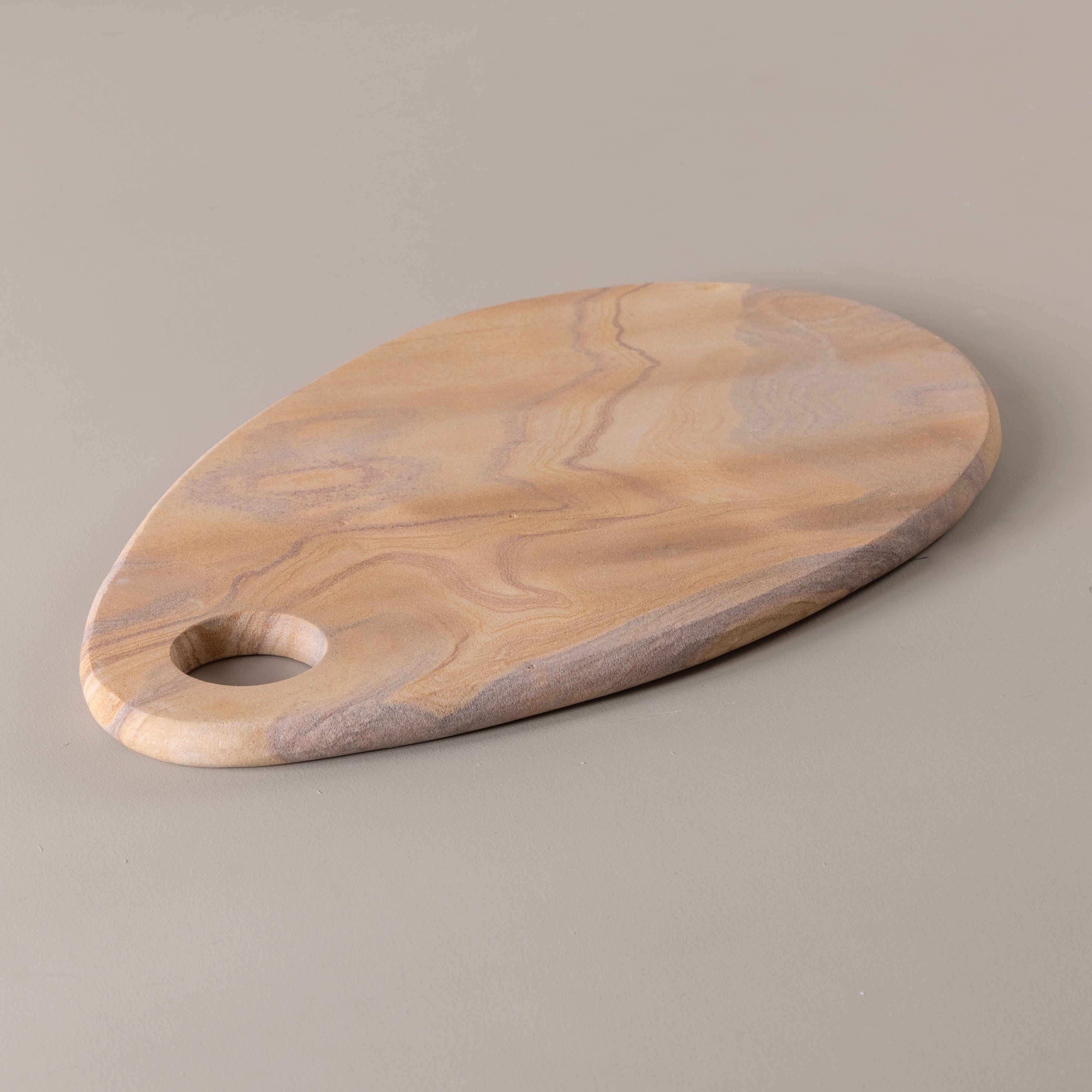 Wooden cutting board with a handle on a gray background