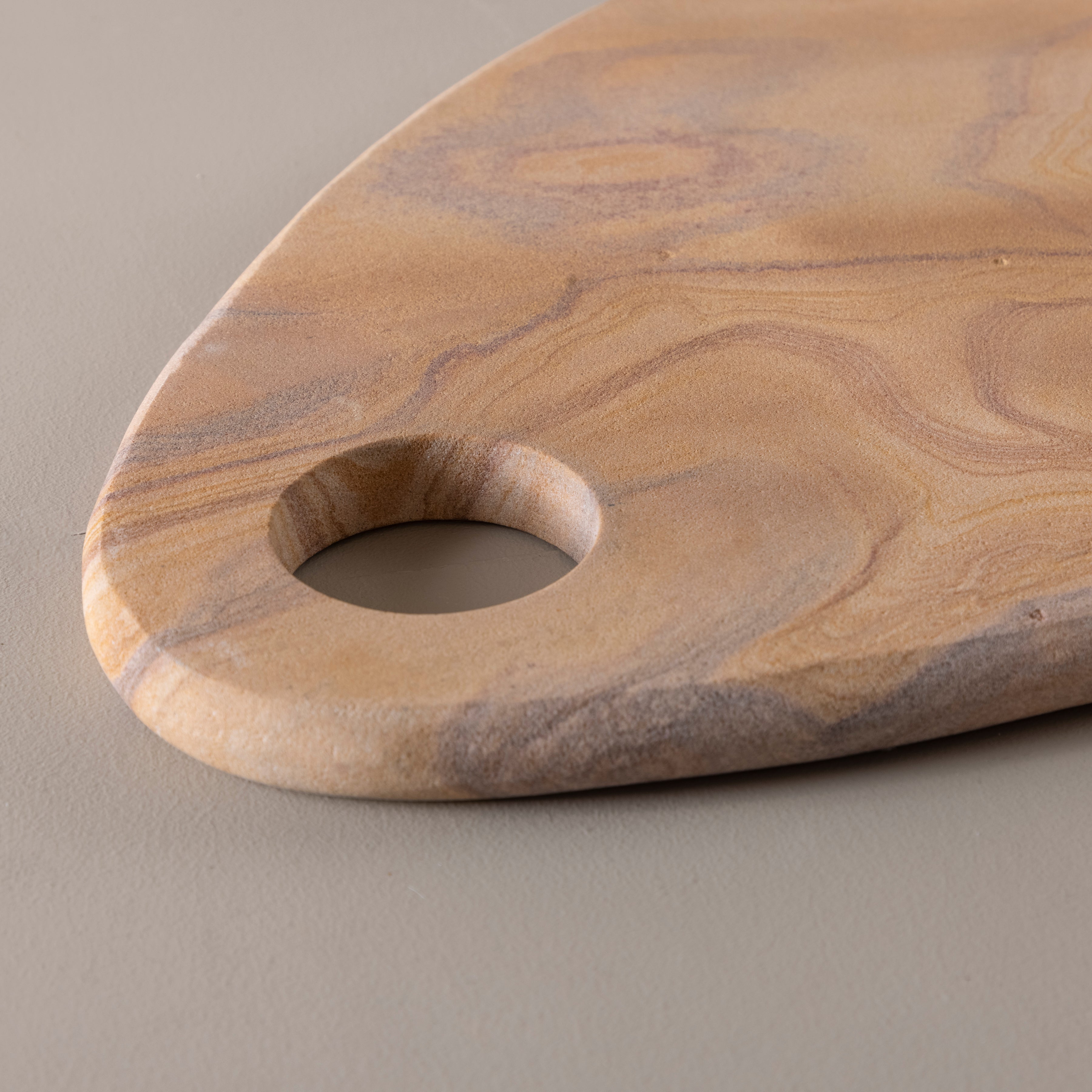 Wooden cutting board with a hole for hanging on a beige background