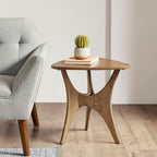 Wooden side table with a cactus and books next to a gray armchair in a room.