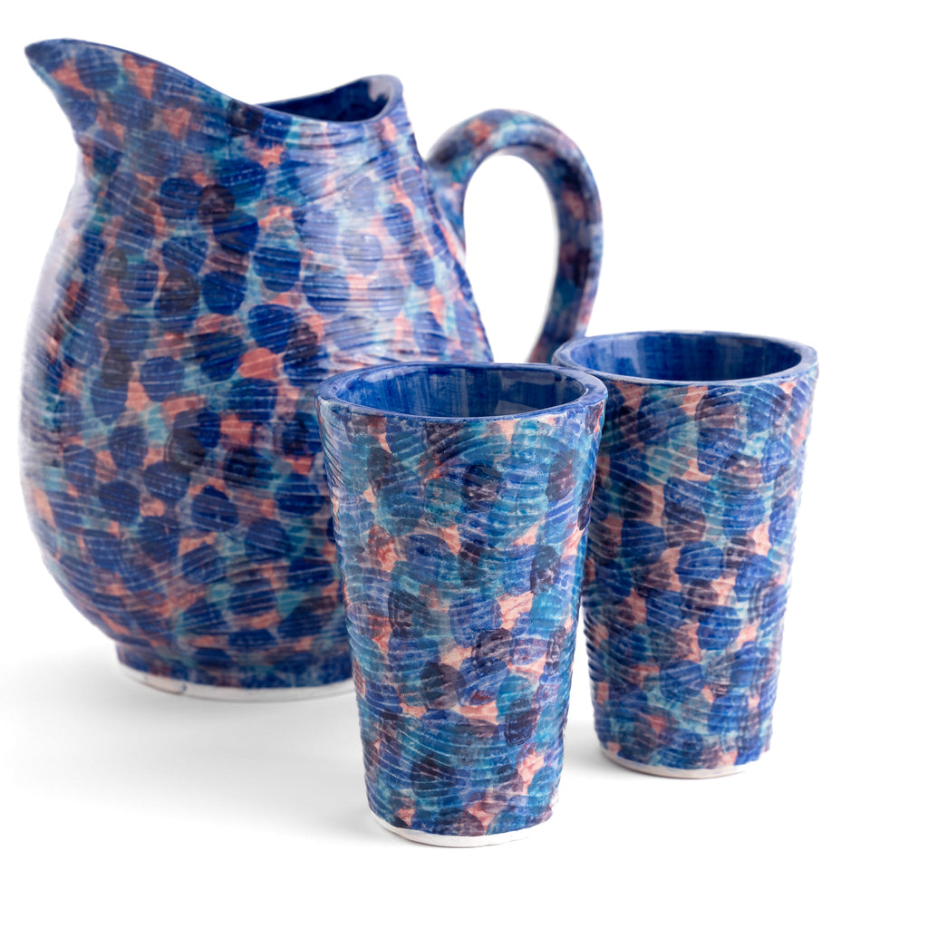 Set of ceramic pitcher and two cups with blue and pink abstract pattern on a white background