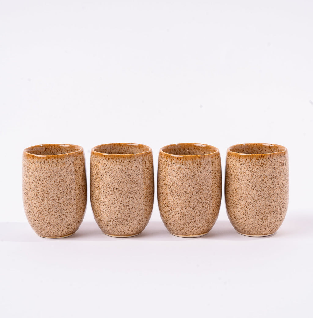 Four brown ceramic tumblers on a white background