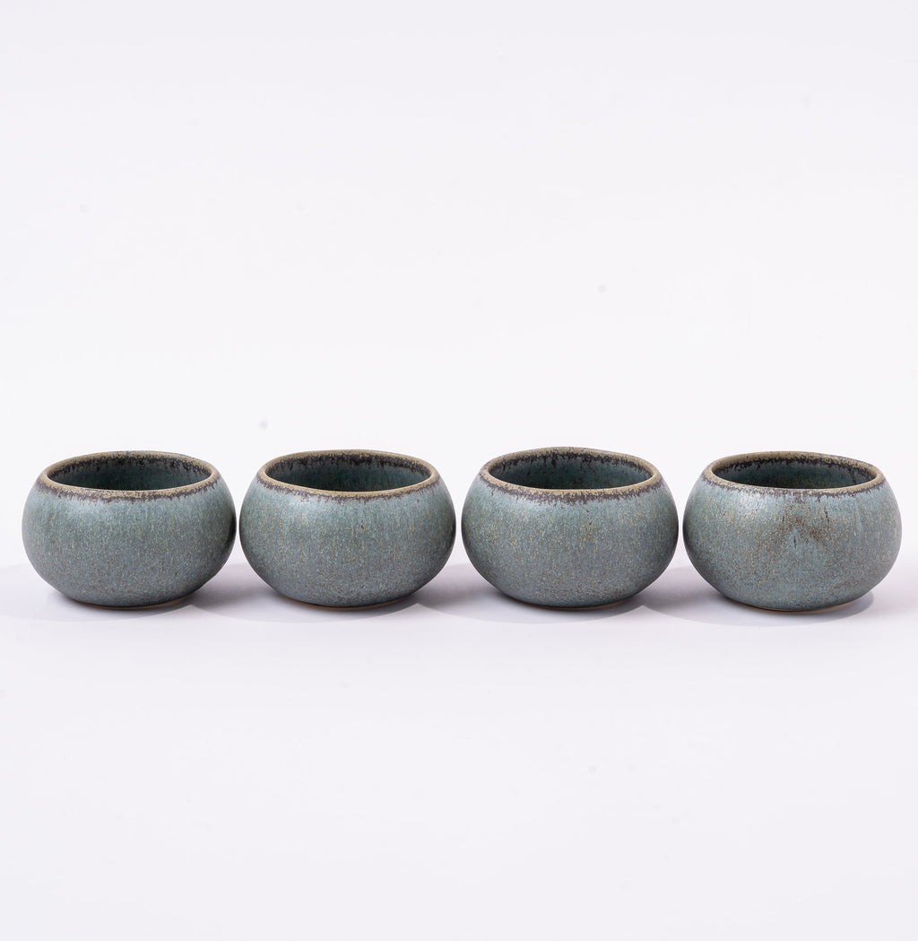 Four ceramic cups with a textured finish on a white background