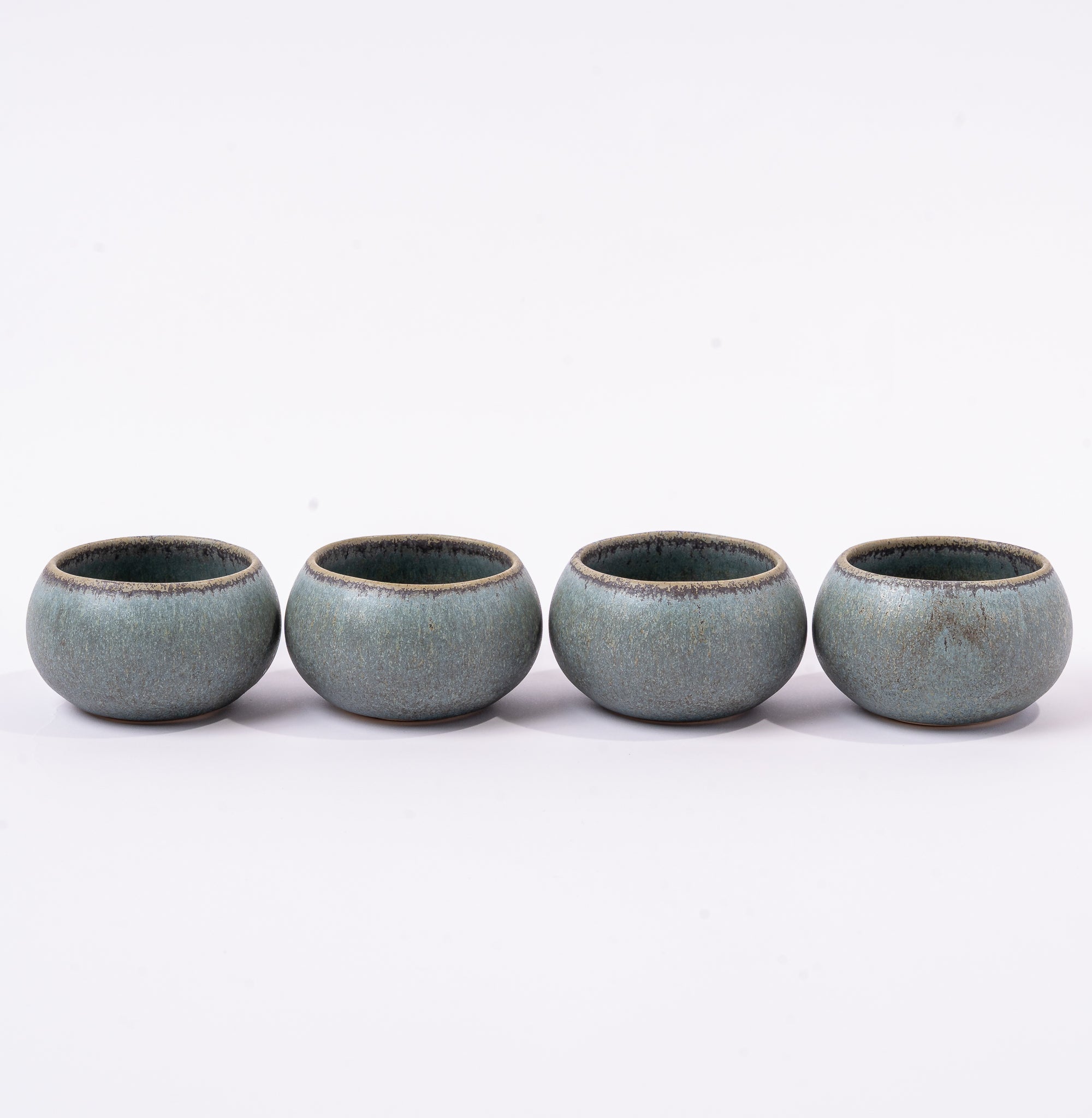 Four ceramic cups with a textured finish on a white background