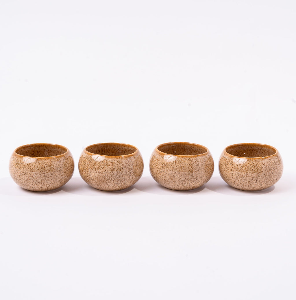 Four ceramic cups with a speckled glaze on a white background