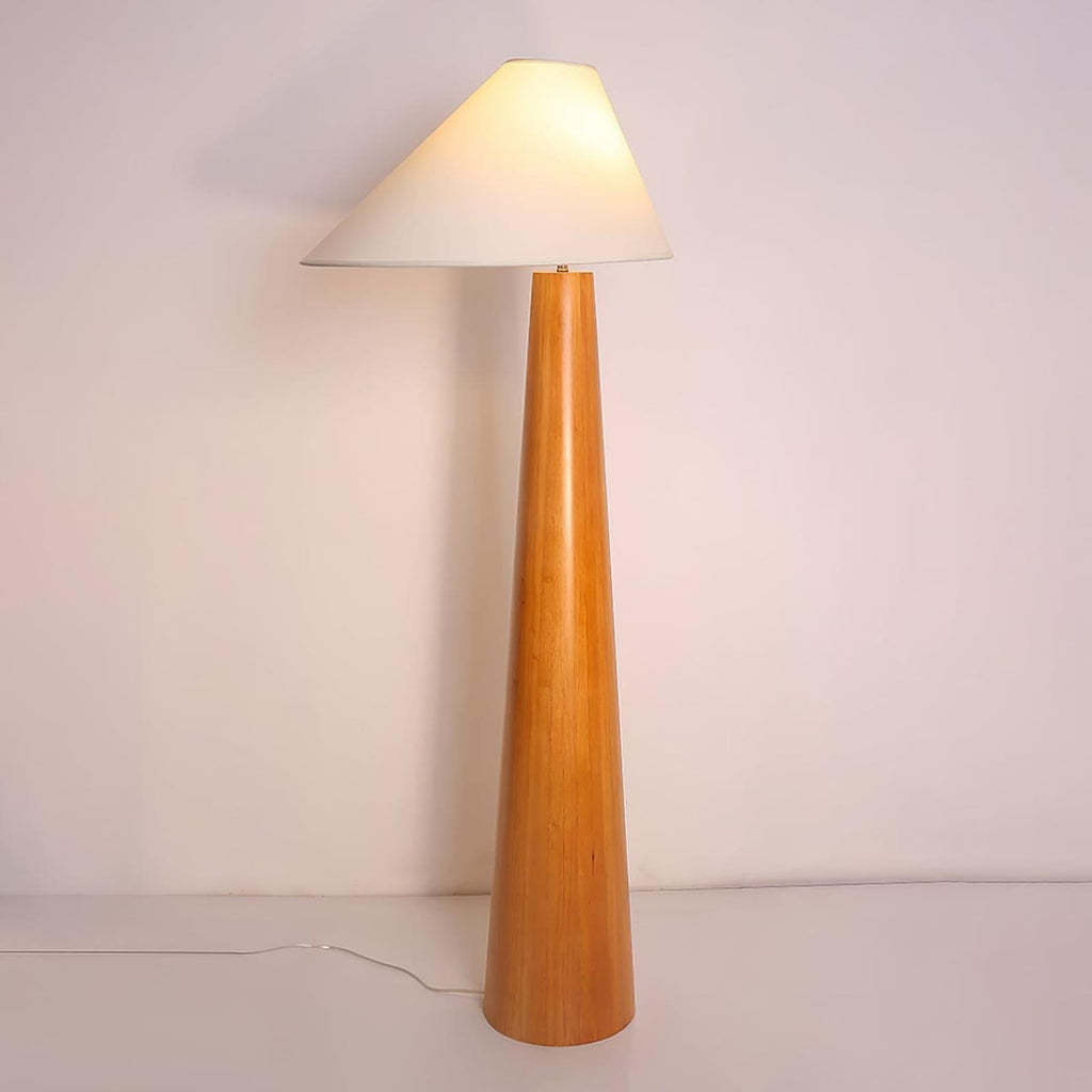 Tall floor lamp with wooden base and white shade on a plain background