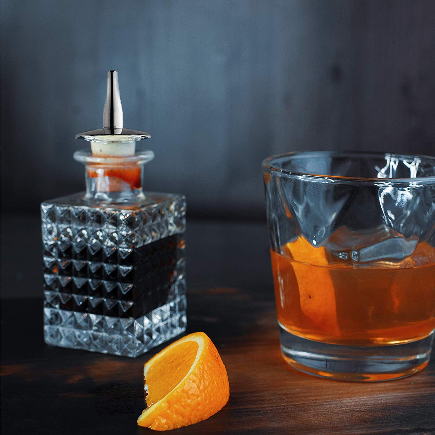 Crystal decanter with a cocktail glass and orange slice on a dark surface
