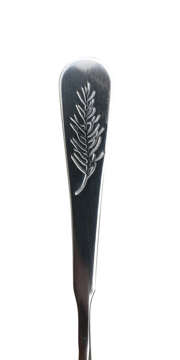 Silver spoon with a rosemary leaf design on a white background