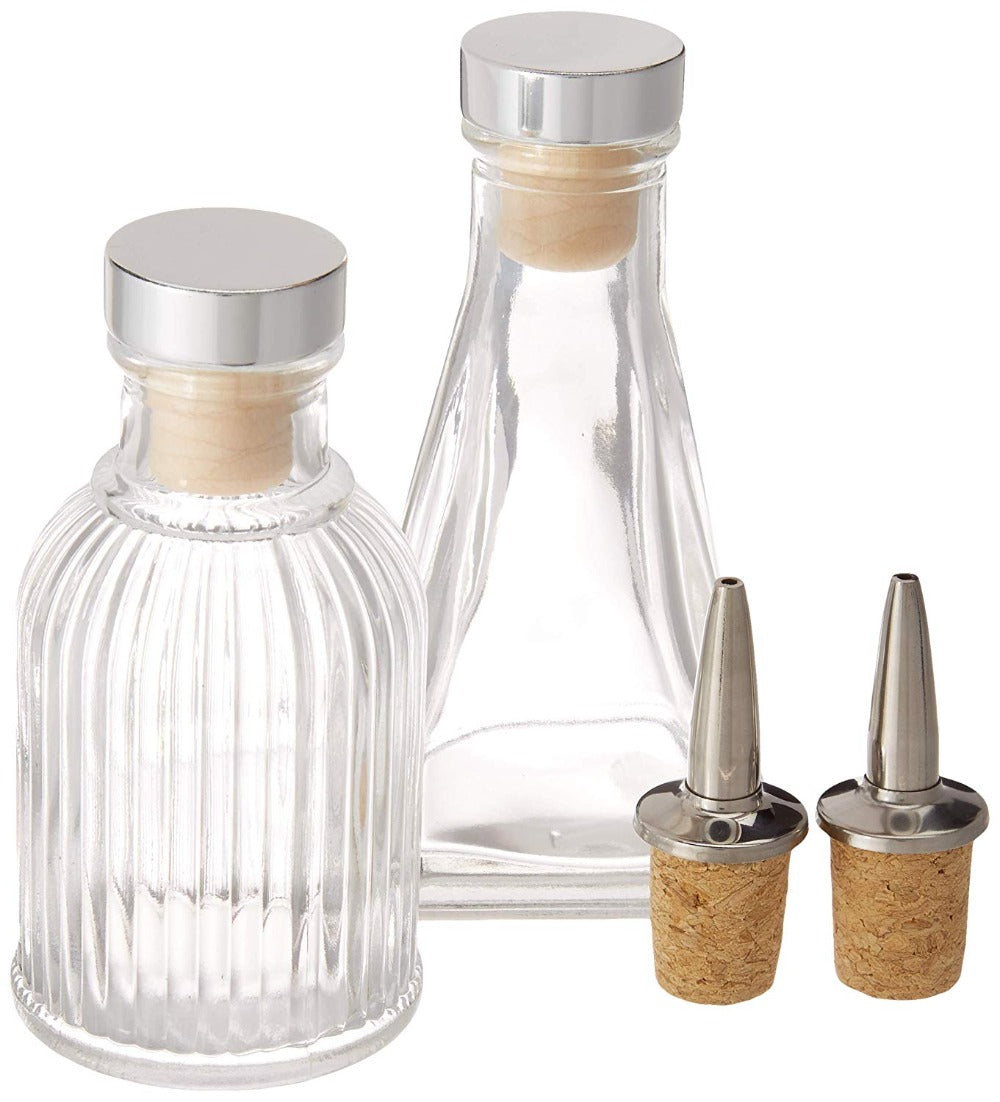 Two glass decanters with silver lids and cork stoppers on a white background