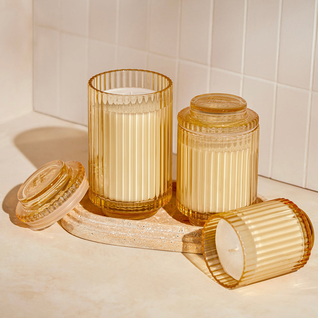 Set of gold glass containers with candles on a white surface.