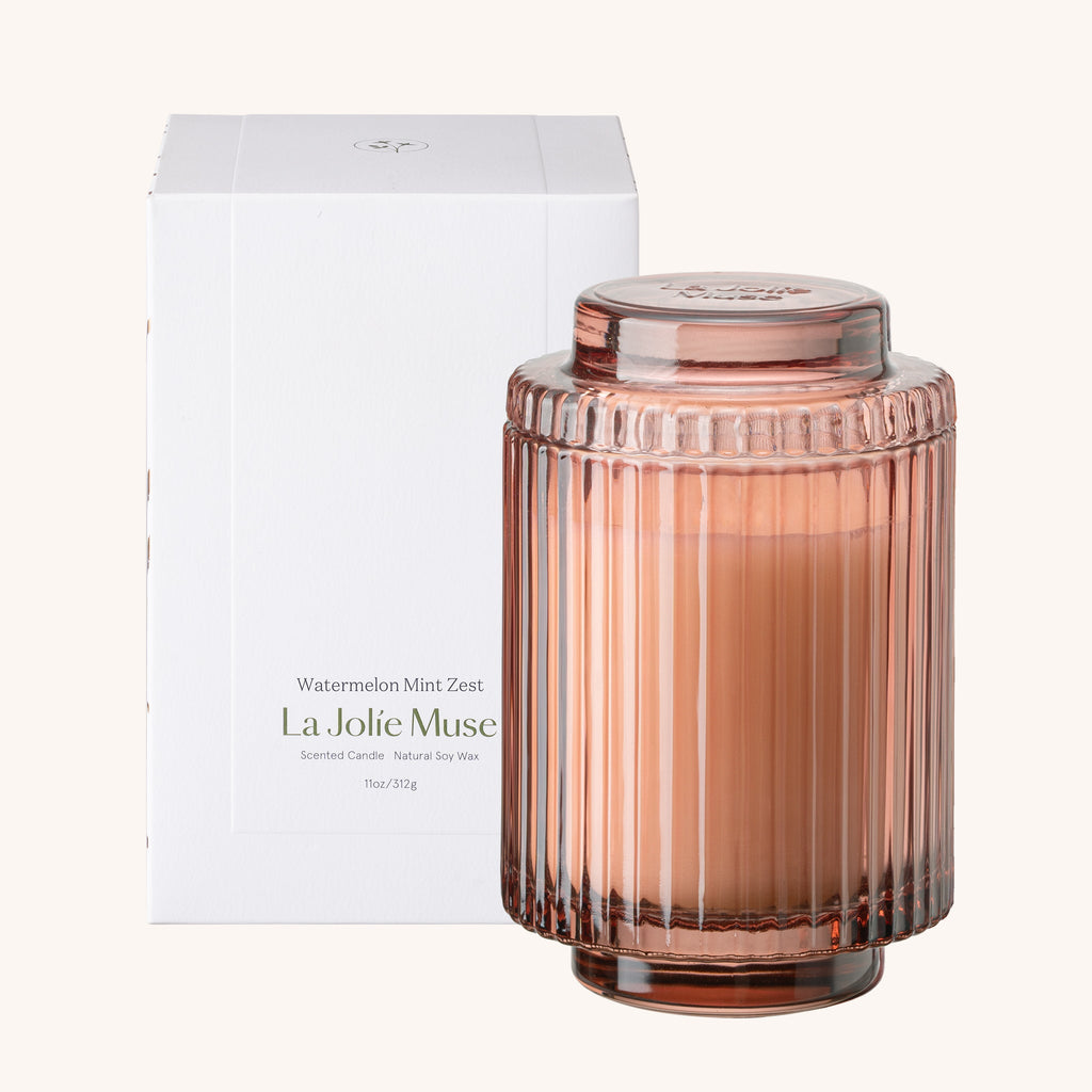 Pink ribbed candle jar with lid and packaging on a white background