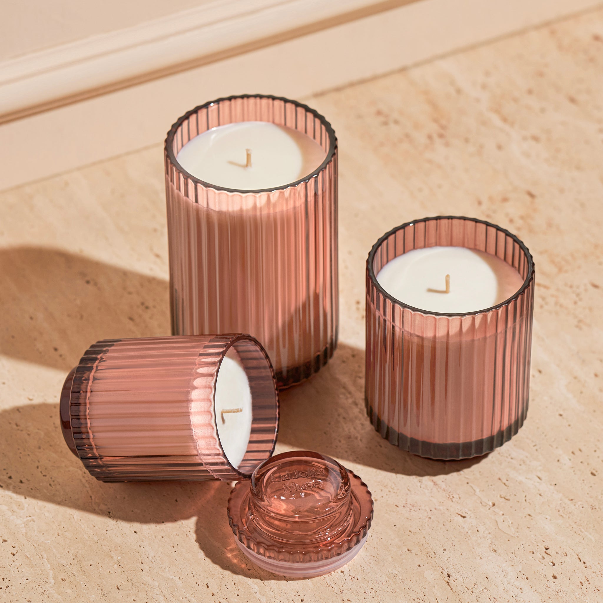 Three ribbed glass candle holders with candles on a wooden surface