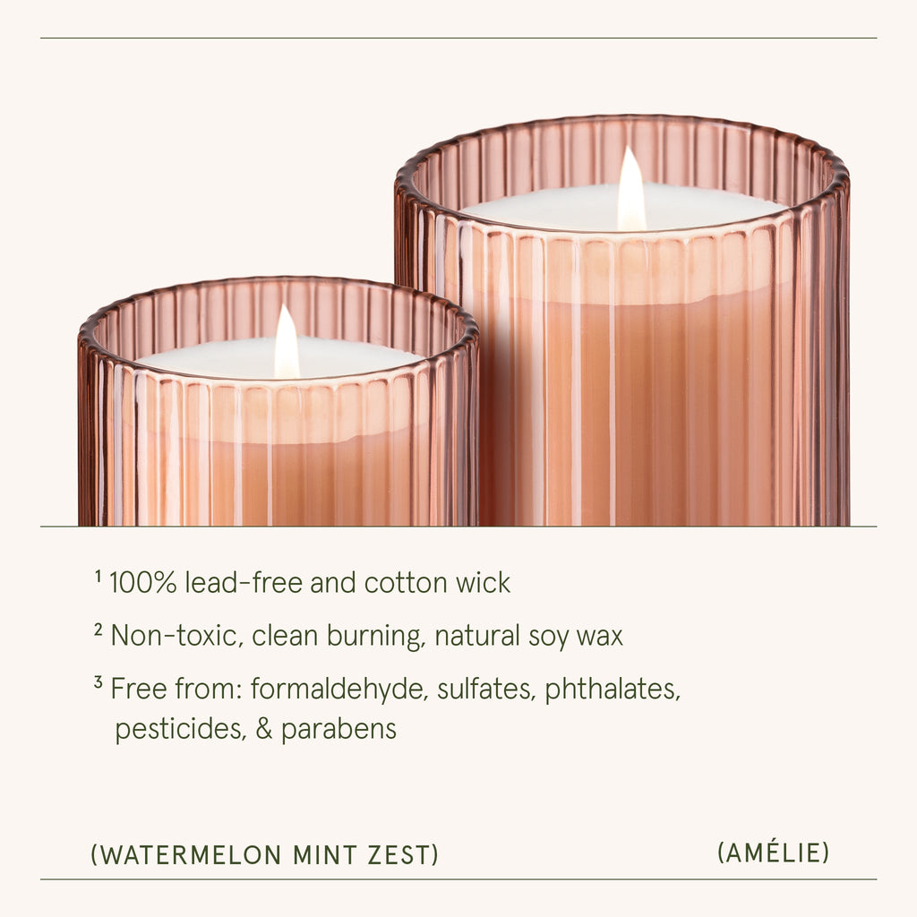 Two pink ribbed glass candles with a white candle inside on a white background.