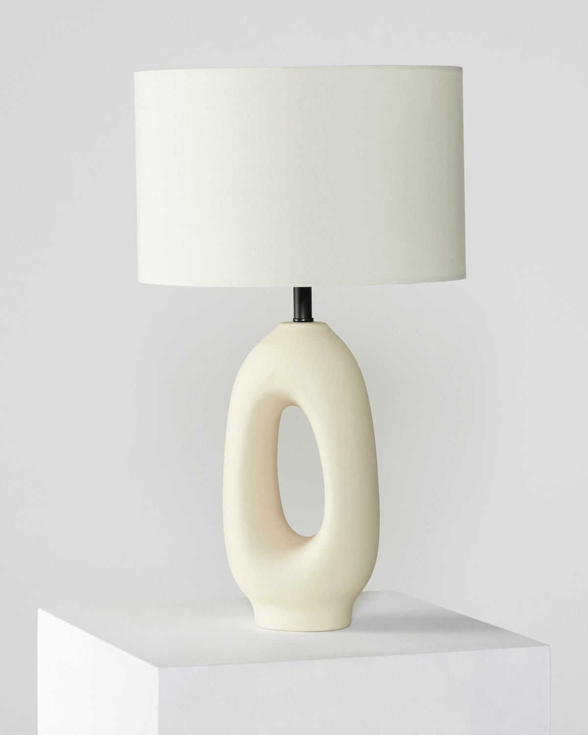 Table lamp with a white ceramic base and beige lampshade on a light gray background