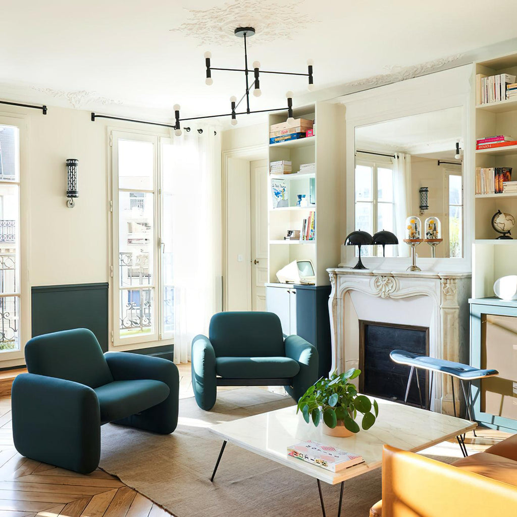 Modern living room with teal armchairs, a coffee table, and a fireplace.