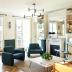 Modern living room with teal armchairs, a coffee table, and a fireplace.