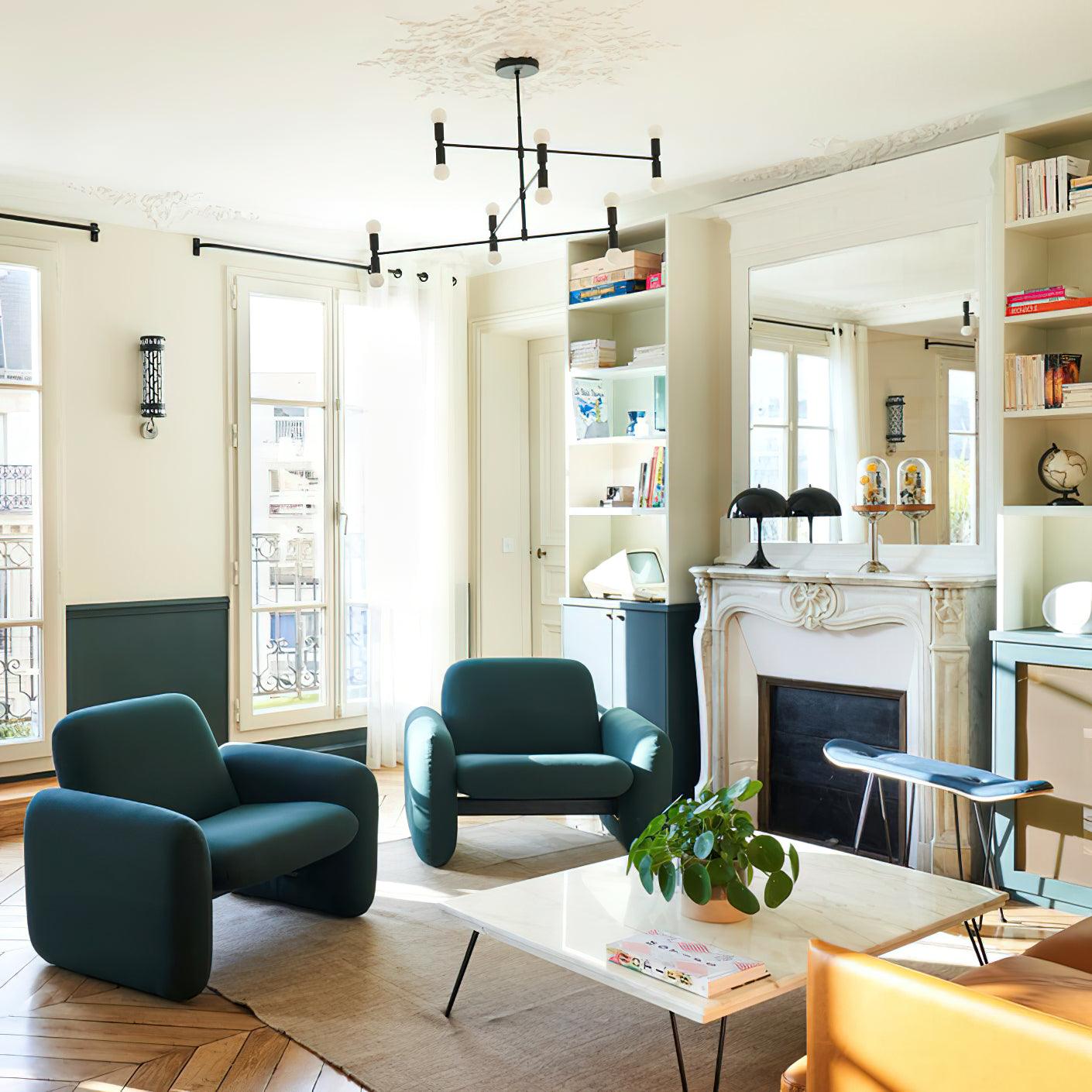 Modern living room with teal armchairs, a coffee table, and a fireplace.