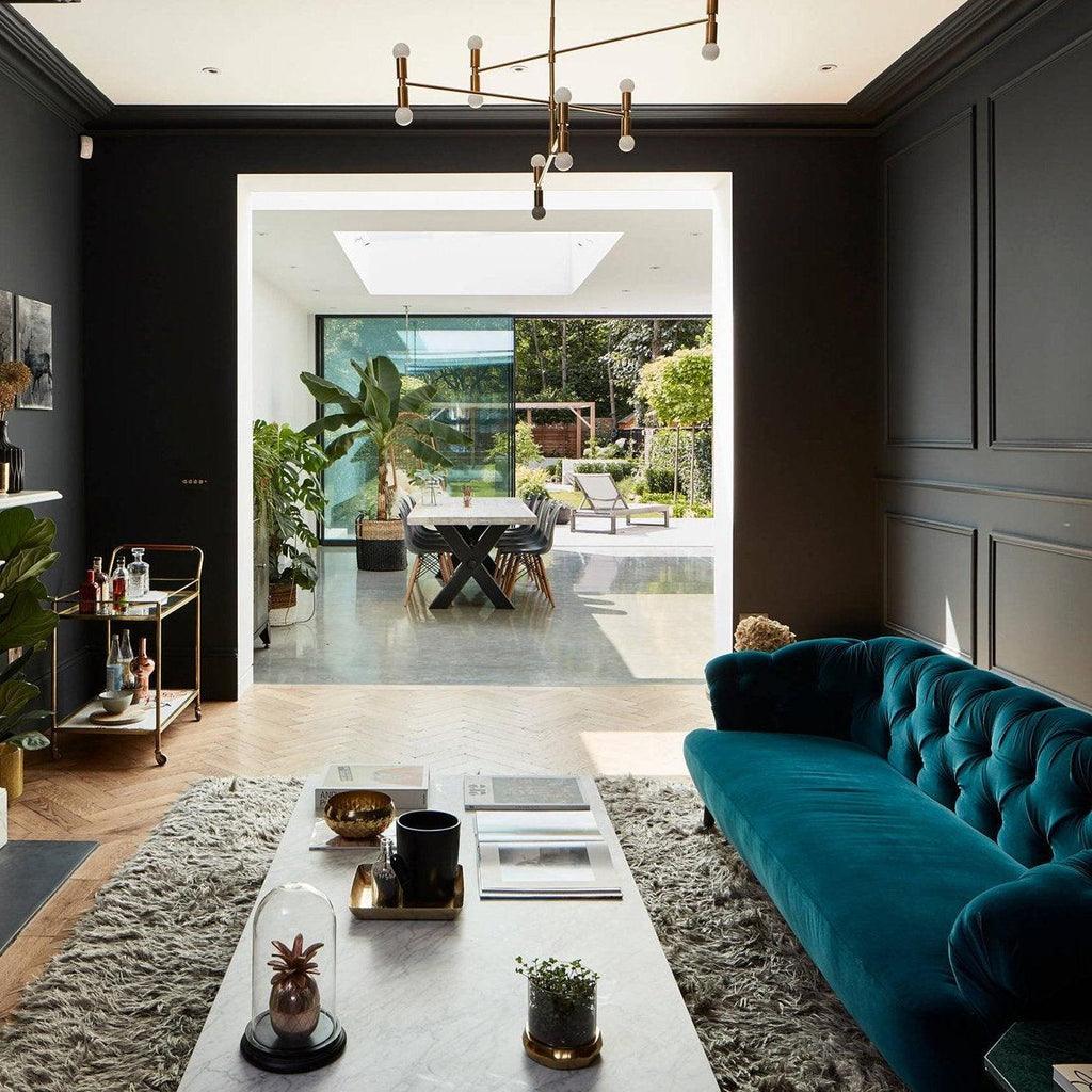 Modern living room with teal sofa, coffee table, and open door to patio.