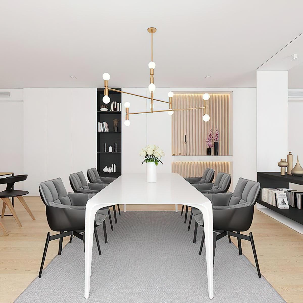 Modern conference room with a long white table and gray chairs, featuring a chandelier and bookshelf.