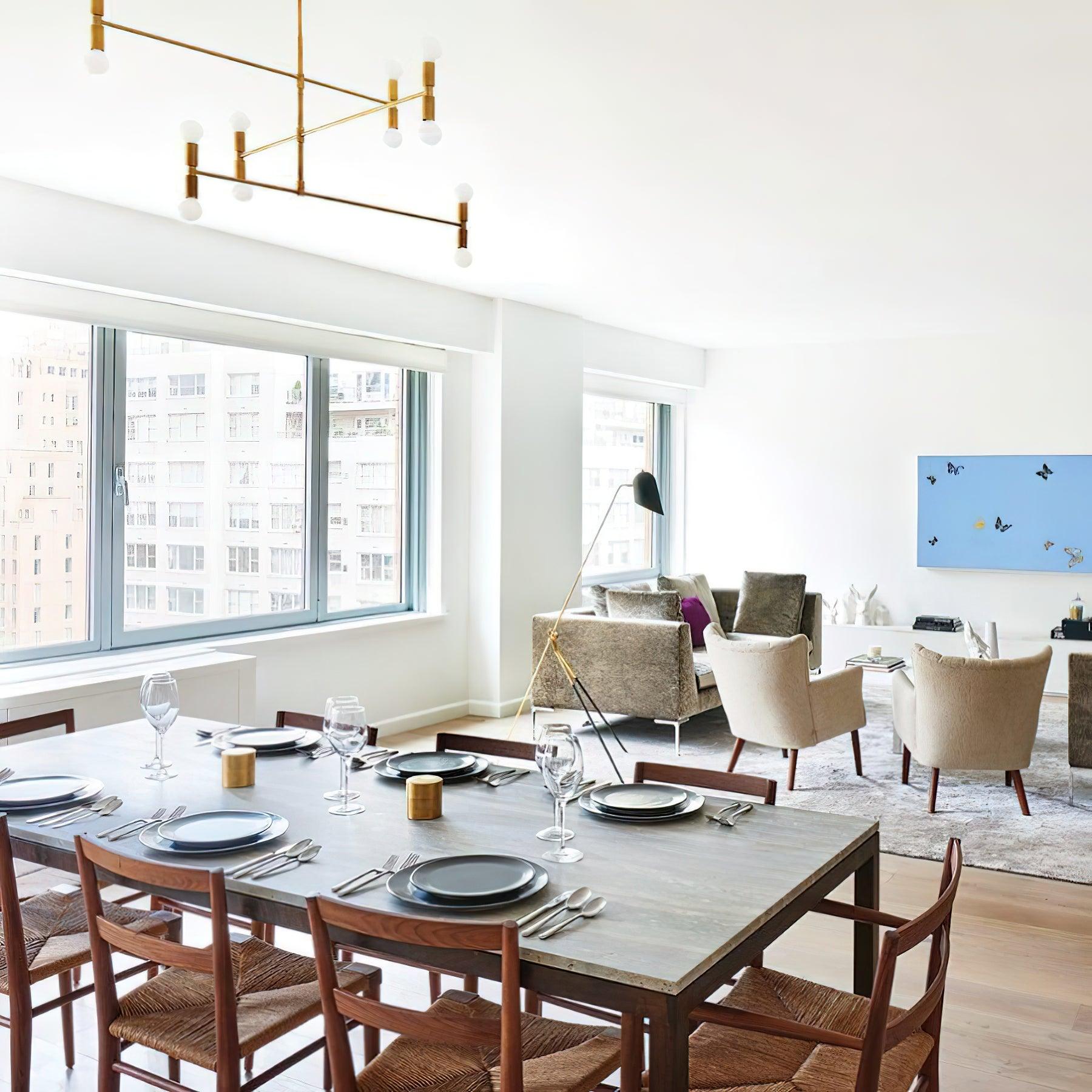 Modern dining room with wooden table and chairs, large windows, and cityscape view.