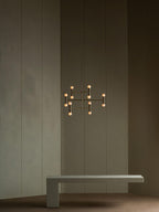 Modern chandelier hanging above a concrete bench against a dark wall.