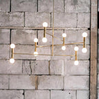 Modern chandelier with multiple lights against a textured stone wall.