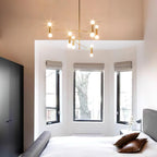 Modern bedroom with a chandelier, bed, and large windows.