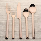 Set of rose gold cutlery on a textured surface