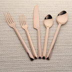 Set of rose gold cutlery on a textured surface