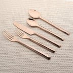 Set of rose gold cutlery on a textured surface