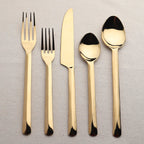 Set of gold cutlery including fork, knife, and spoons on a textured surface