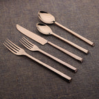 Set of bronze cutlery including knife, fork, and spoons on a textured surface.