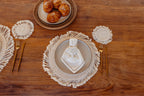 Table setting with decorative plates, gold cutlery, and pastries on a wooden surface.