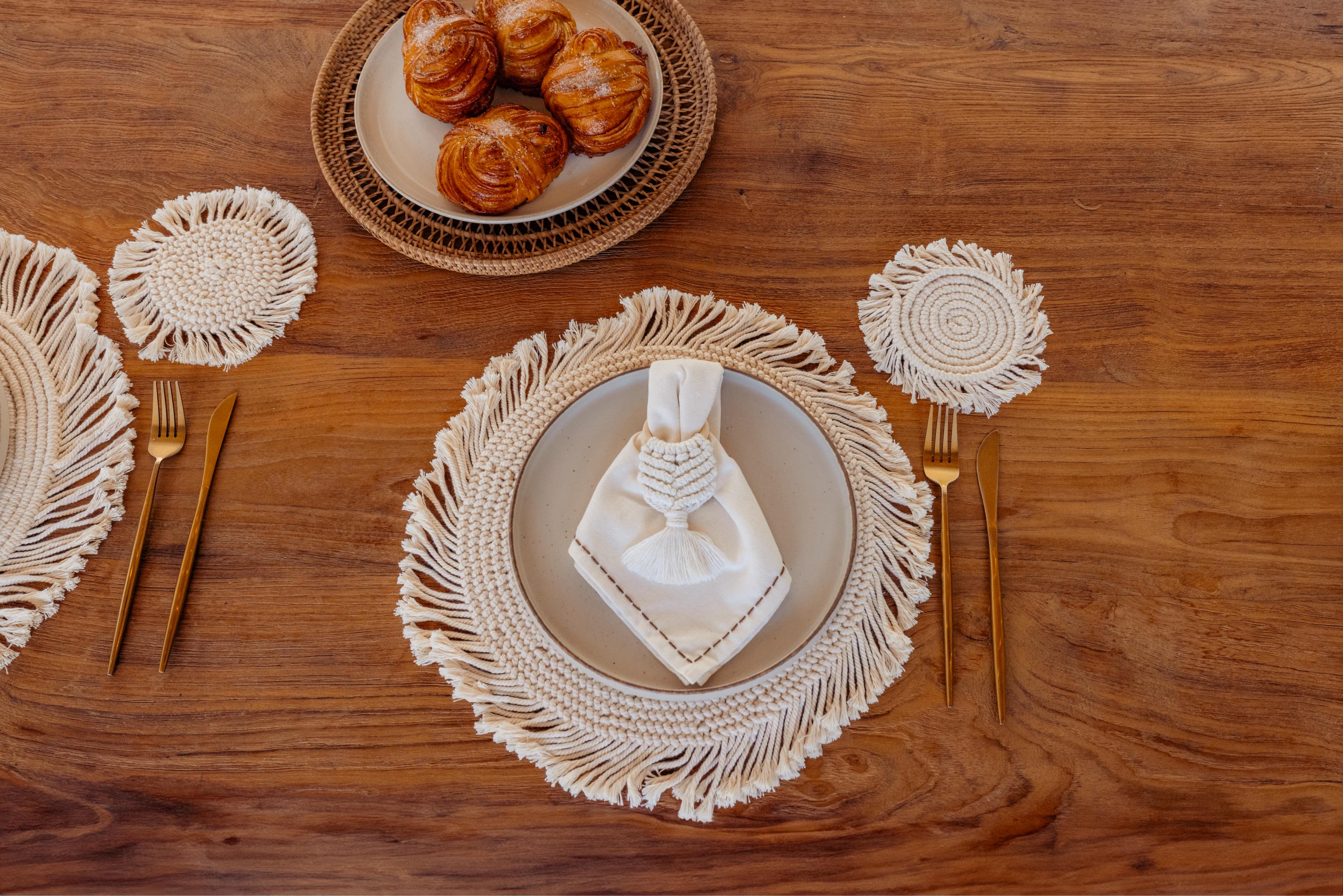 Table setting with decorative plates, gold cutlery, and pastries on a wooden surface.