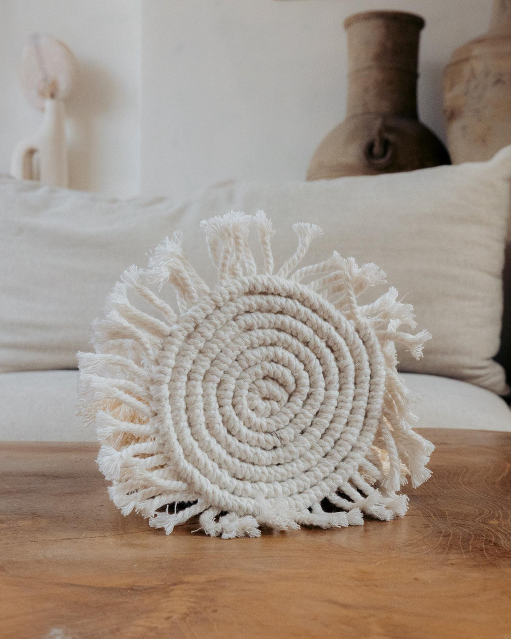 Round woven decorative item on a wooden surface with neutral background