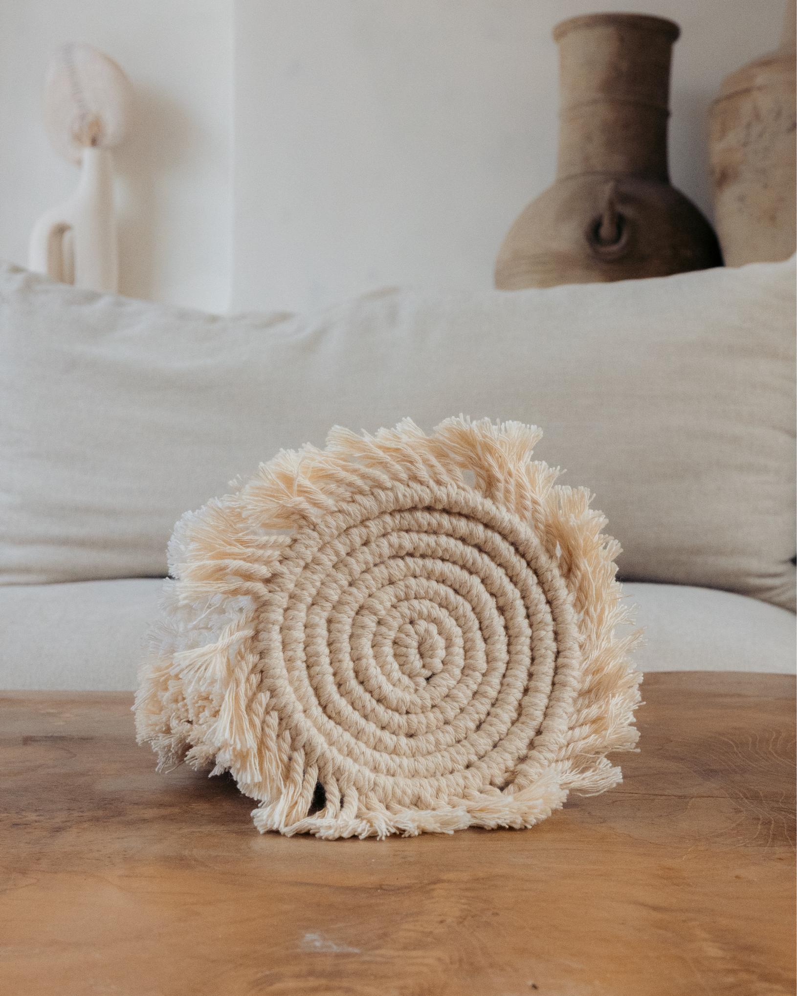 Decorative woven pillow on a wooden surface with a neutral background