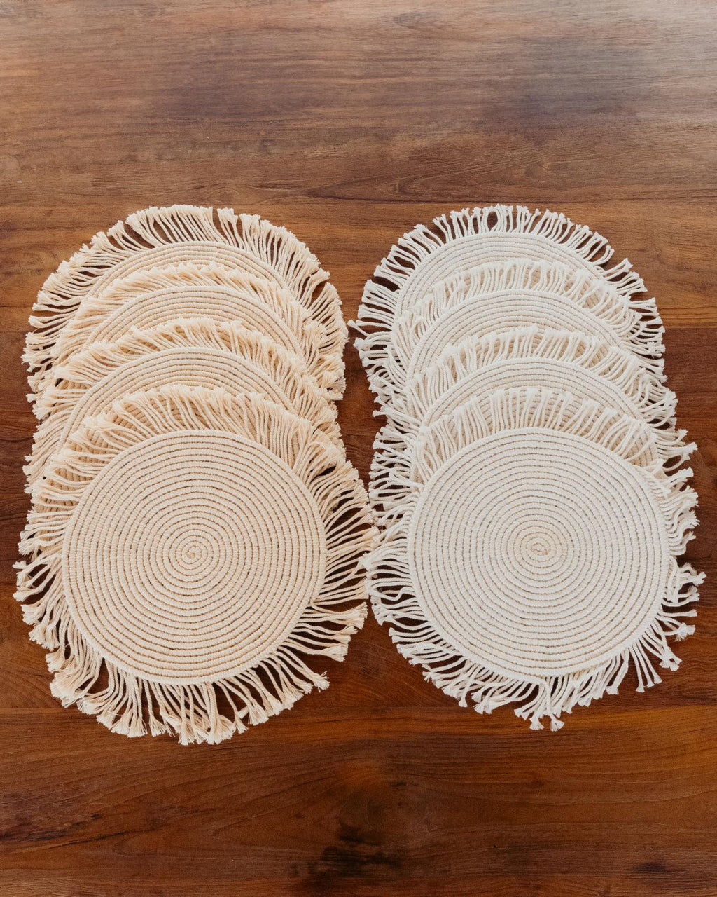 Set of round woven placemats with fringes on a wooden surface