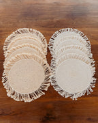 Set of round woven placemats with fringes on a wooden surface