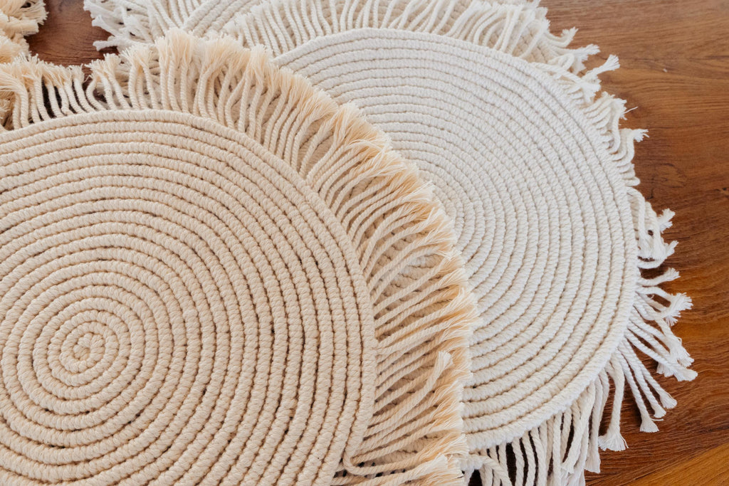 Round woven placemats with fringe on a wooden surface