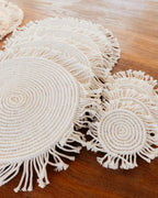 Set of round woven coasters with fringes on a wooden surface