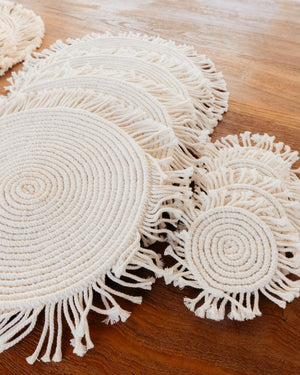 Set of round woven coasters with fringes on a wooden surface