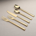 Set of gold cutlery including knife, fork, and spoons on a neutral background