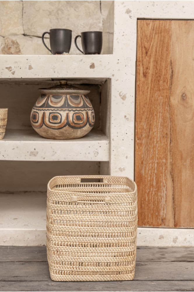 Woven rattan basket on a wooden floor with a rustic shelf in the background