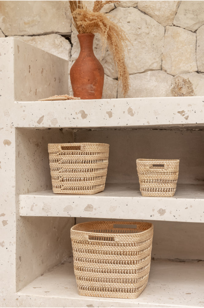 Woven baskets on a stone shelf with a terracotta vase.